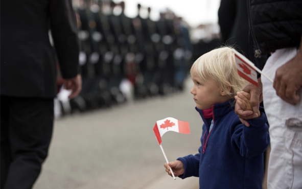 Child holding a small Canadian flag in a street