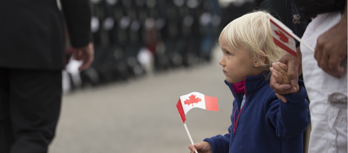 Child holding a small Canadian flag in a street